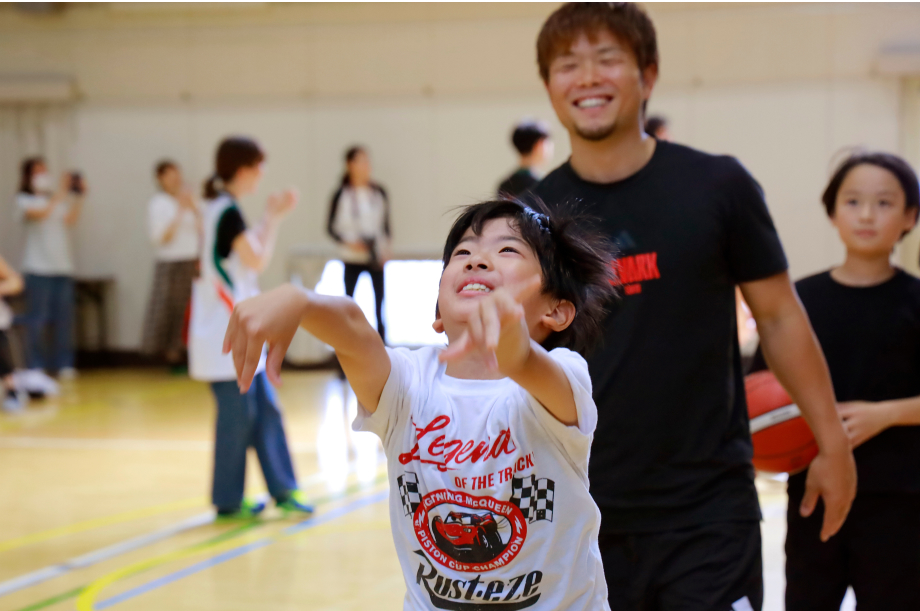 アルバルク東京の岡本選手に見守られながら子供がシュートを打っている写真
