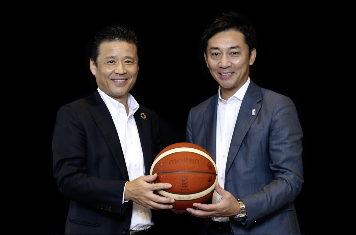 南社長と島田チェアマンが二人の間にある一つのボールを胸の下で持っている写真