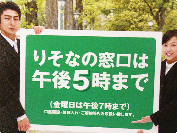 「りそなの窓口は午後5時まで」と記載された紙を銀行員が持っている写真