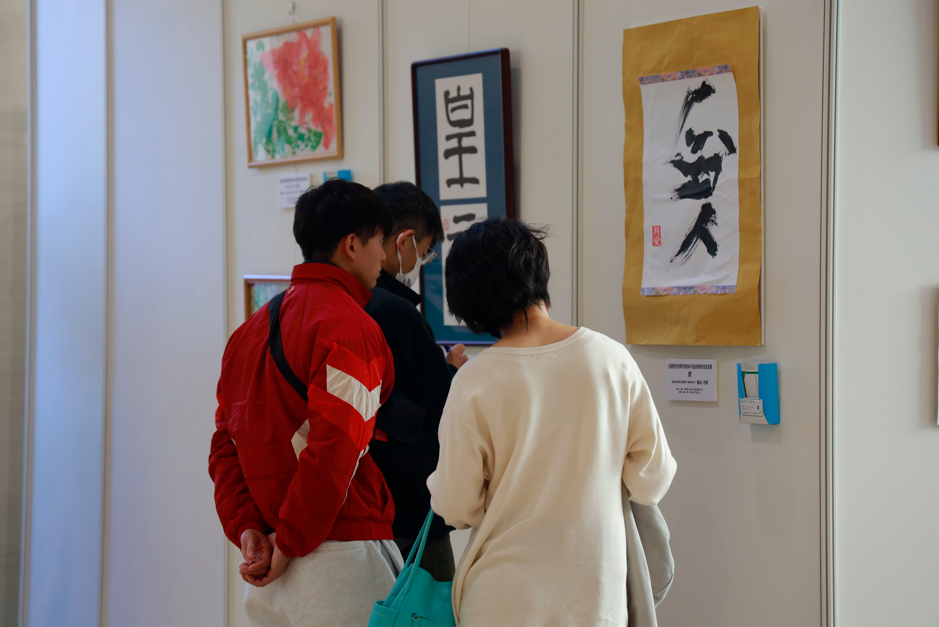 壁に掛けられた受賞作品を３人で見ている様子