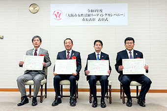 表彰式にて認定証を持つ受賞者4名が並ぶ様子