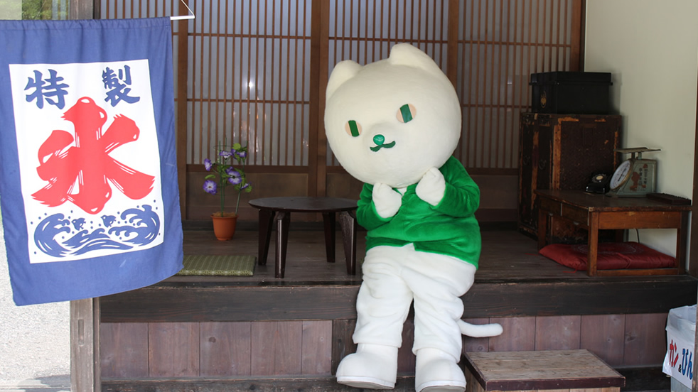 りそにゃが氷の看板が出ている店の入り口に座っている画像